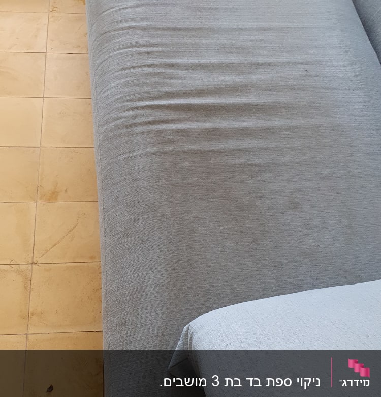 ספה אפורה עם כרית על רצפה מרוצפת